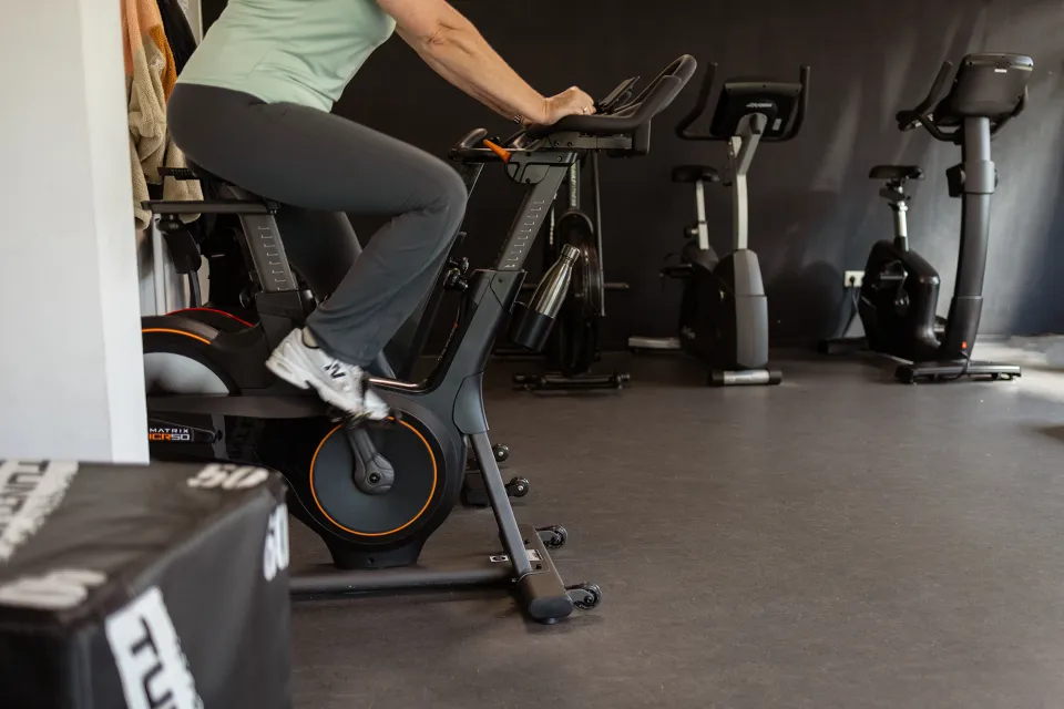 Een sporter traint op een fiets naast de cardiotoestellen in de RevaPoint gym